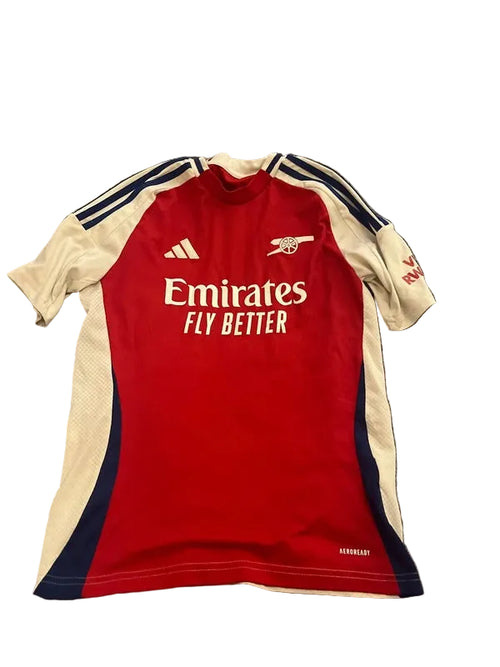 Red and beige sports jersey with Emirates logo on a textured surface